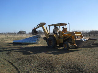 Backhoe Holding Culvert Pipe