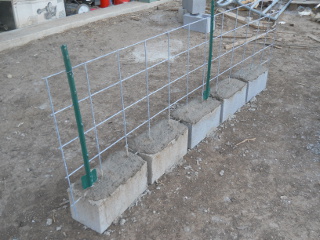 Pig fence piece concreted in cinder blocks