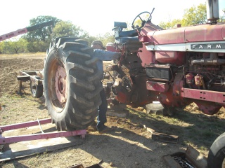 Farmall 806 Rear Tractor Wheel Held Up by Engine Hoist